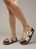 White sandals with gold accents worn by a person on a white floor.